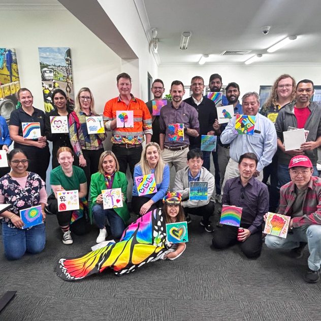 Group of Diona employees holding up their Pride-themed artworks at the Pride event.